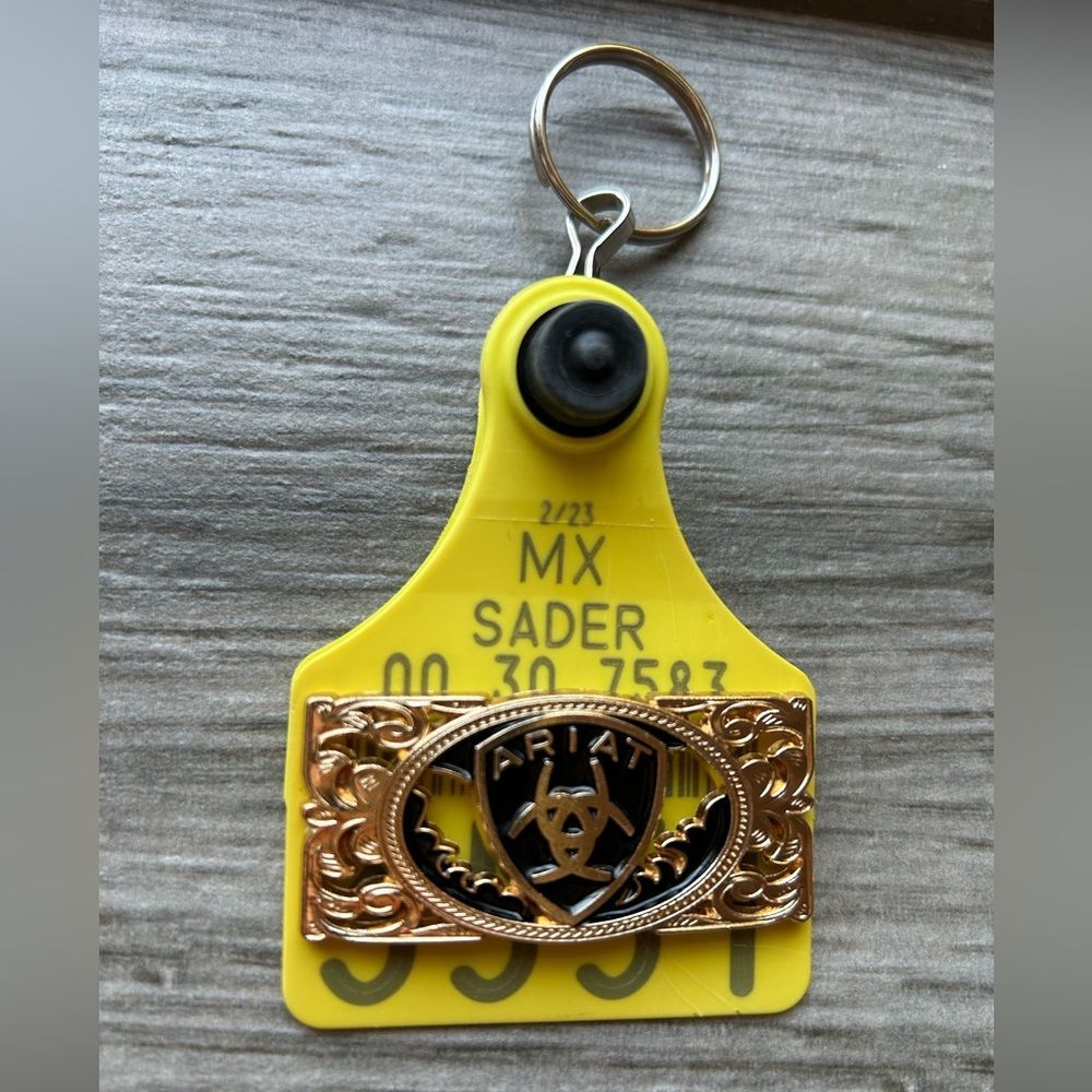 Arete De Vaca Llavero Cattle Tag Western Keychain with Ariat emblem.
